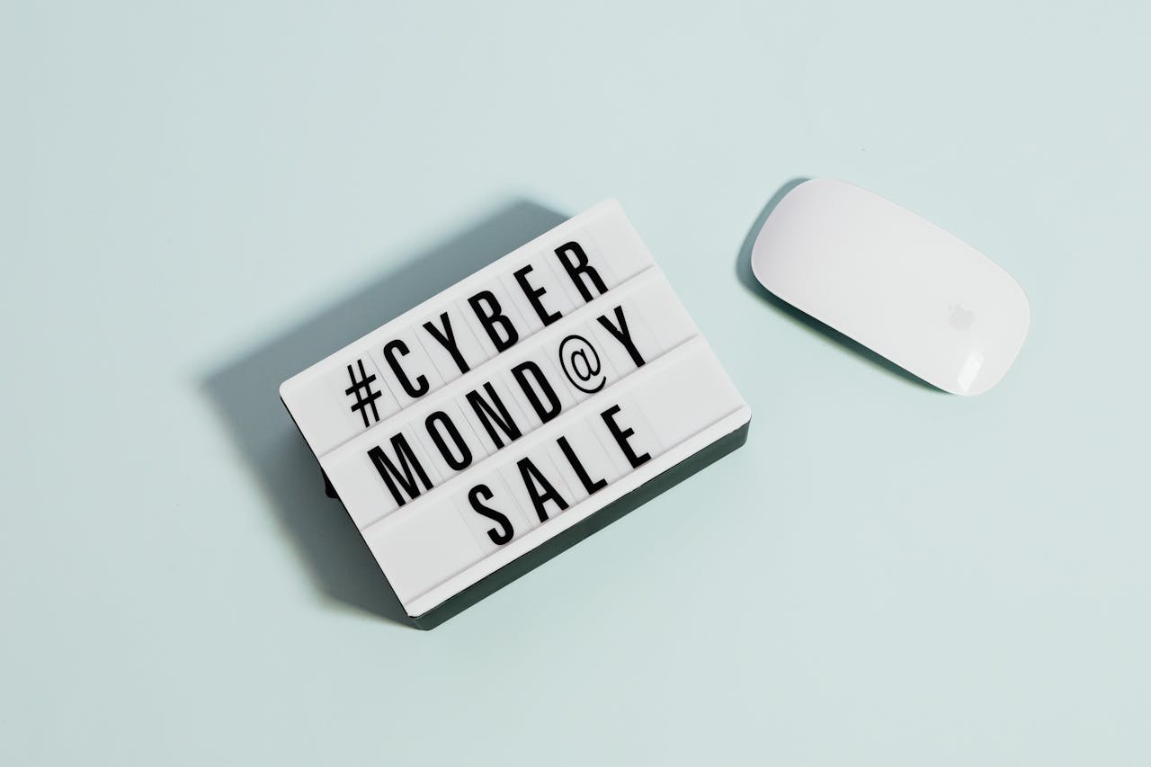 Lightbox sign displaying 'Cyber Monday Sale' beside a computer mouse on a pastel background.
